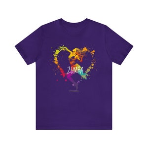 May include: A purple t-shirt featuring a colorful Zumba design. The design includes a silhouette of a dancing figure inside a heart-shaped splash of rainbow colors, with the word "ZUMBA" in white.