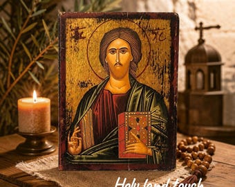 May include: A rectangular wooden icon featuring a painted portrait of Jesus Christ with a gold background, dark red and green robes, and a halo. The figure holds a red book with gold accents. The text "Holy land touch" is visible at the bottom.