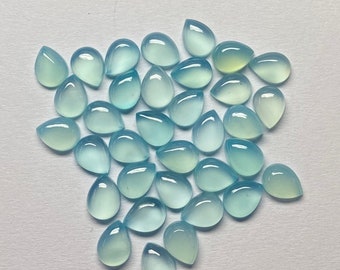 May include: A collection of teardrop-shaped gemstones in varying shades of blue and green. The polished stones are translucent, with a smooth, glossy surface. The gemstones are arranged on a light-colored surface, creating a visually appealing display.
