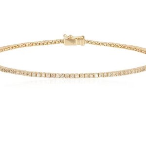 Puede incluir: Un brazalete de tenis de oro con una fila de peque&ntilde;os diamantes transparentes.