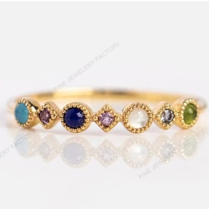 Puede incluir: Anillo de oro con siete piedras preciosas de colores. El anillo presenta una turquesa, una amatista, un zafiro, una amatista, una perla, un zafiro y una esmeralda.