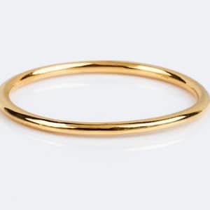 Könnte beinhalten: Nahaufnahme eines dünnen, goldfarbenen Rings. Der Ring ist kreisförmig und hat eine glatte, polierte Oberfläche. Der Ring ist vor einem weißen Hintergrund platziert, was seine schlichte Eleganz hervorhebt. Der Ring scheint aus Metall zu sein.