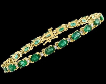Puede incluir: Una pulsera dorada con esmeraldas ovaladas y pequeños diamantes. La pulsera tiene un cierre y está sobre un fondo negro. Las esmeraldas son de color verde vibrante.
