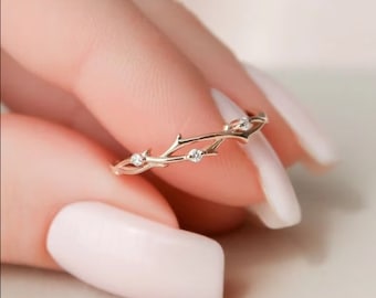 May include: A delicate gold ring with a twig design and small clear stones.