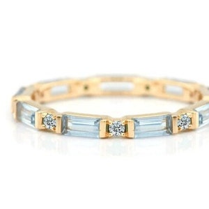 Könnte beinhalten: Ein Goldring mit einer Reihe von baguetteförmigen blauen Edelsteinen und runden Diamanten.
