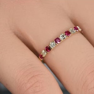 Peut inclure: Une bague en or avec des rubis rouges et des diamants clairs alternés.