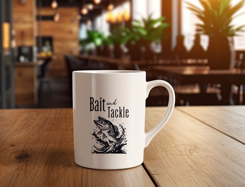 May include: White ceramic coffee mug with a black and white illustration of a fish jumping out of the water. The text "Bait and Tackle" is printed on the mug.