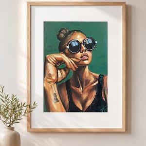 Könnte beinhalten: Ein gerahmtes Gemälde mit dem Porträt einer Person mit Dutt, die eine große runde schwarze Sonnenbrille und ein schwarzes Tanktop trägt. Die Person hat ein kleines Schachfiguren-Tattoo auf dem Unterarm und ist vor einem grünen Hintergrund.