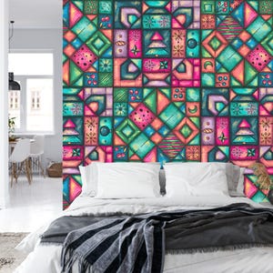 K&ouml;nnte beinhalten: Eine farbenfrohe geometrische Tapete in T&uuml;rkis-, Rosa-, Orange- und Gr&uuml;nt&ouml;nen ziert eine Schlafzimmerwand. Das Design zeigt Quadrate und Rechtecke mit verschiedenen Formen. Ein Bett mit wei&szlig;er Bettw&auml;sche und einer grauen Decke befindet sich vor der Wand.