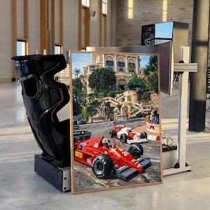 Könnte beinhalten: Gerahmtes Gemälde eines roten Formel-1-Rennwagens mit der Nummer 27 auf einer Rennstrecke. Das Gemälde befindet sich vor einem schwarzen Rennsitz und einem Computermonitor.