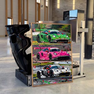 May include: A rectangular framed print featuring three Porsche race cars in green, pink, and white, each decorated with a shark-tooth graphic on the front bumper and the number 77, set against a background with colorful paint splatters.
