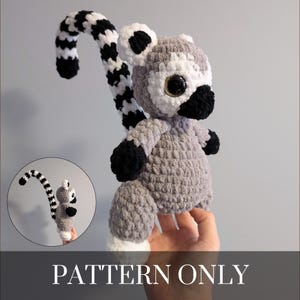 May include: A crocheted lemur plushie with a long, striped tail. The lemur is primarily gray with white accents on the face, ears, and feet, and black on the nose, hands, and tail stripes. The text "PATTERN ONLY" is displayed at the bottom.