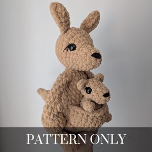 May include: A tan crochet kangaroo with a joey in its pouch. The kangaroo has black eyes and a black nose. The text "PATTERN ONLY" is displayed at the bottom of the image.