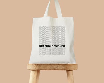 May include: White tote bag with the text "GRAPHIC DESIGNER" repeated in a pattern on the front.