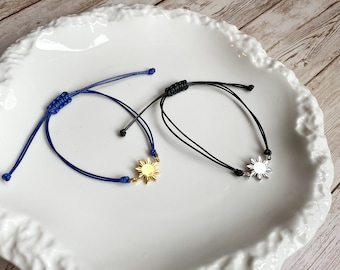 May include: Two adjustable bracelets with sun charms. One bracelet is blue and the other is black.