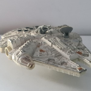 Könnte beinhalten: Ein Miniatur-Raumschiffmodell aus cremefarbenem und grauem Kunststoff mit kreisförmigem Rumpf, einem oben montierten Geschützturm, einer kleinen Radarschüssel und detaillierten mechanischen Oberflächenstrukturen.