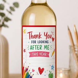 May include: A clear glass wine bottle with a red screw cap and a white rectangular label featuring lined paper graphics. The label displays the text "Thank You FOR LOOKING AFTER ME THIS YEAR" in red, blue, and green, surrounded by colorful pencil, heart, star, and apple illustrations.