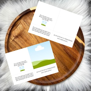 Puede incluir: Dos tarjetas blancas plegadas con ilustraciones de paisajes y texto. Las tarjetas están sobre una bandeja de madera con un fondo de piel blanca. El texto en las tarjetas incluye "Esta es la parte posterior de tu tarjeta. Agrega el logotipo de tu empresa aquí o incluso un código QR."