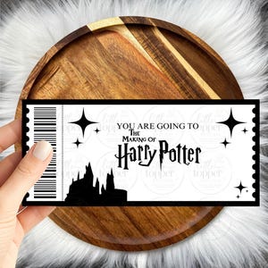 Może przedstawiać: Czarno-biały bilet z napisem "YOU ARE GOING TO THE MAKING OF Harry Potter". Bilet przedstawia sylwetkę zamku i akcenty gwiazd. Bilet jest trzymany nad drewnianą tacą.