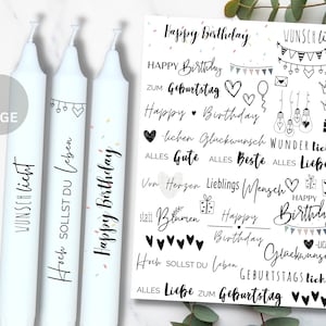 May include: Three white candles with black lettering. The candles are decorated with confetti and hearts. The text on the candles reads "Wunsch Licht", "Hoch Sollst Du Leben", and "Happy Birthday".