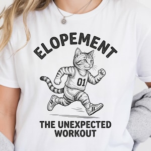 May include: White t-shirt with the word "ELOPEMENT" arched across the top. Below is a running cat wearing a jersey with the number "01". The text "THE UNEXPECTED WORKOUT" is printed below the cat illustration.