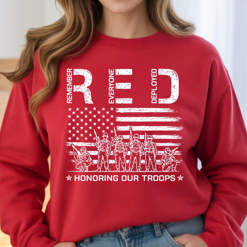 K&ouml;nnte beinhalten: Rotes Sweatshirt mit wei&szlig;er Grafik der amerikanischen Flagge und Soldaten. Der Text lautet &bdquo;REMEMBER EVERYONE DEPLOYED&ldquo; und &bdquo;HONORING OUR TROOPS&ldquo;. Das Sweatshirt hat eine einfarbige rote Farbe.