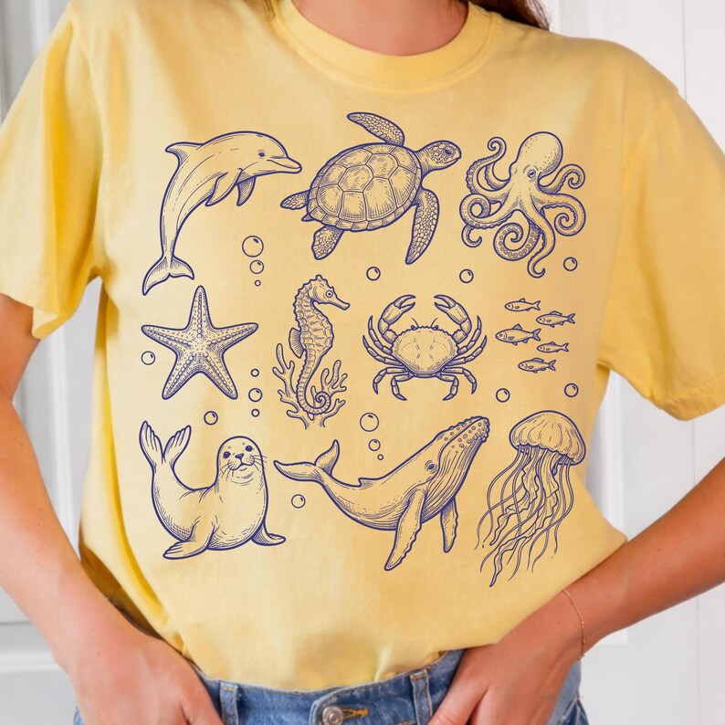 May include: Yellow t-shirt featuring blue line art illustrations of various sea creatures, including a dolphin, turtle, octopus, starfish, seahorse, crab, fish, seal, whale, and jellyfish. The shirt is a casual, comfortable style.