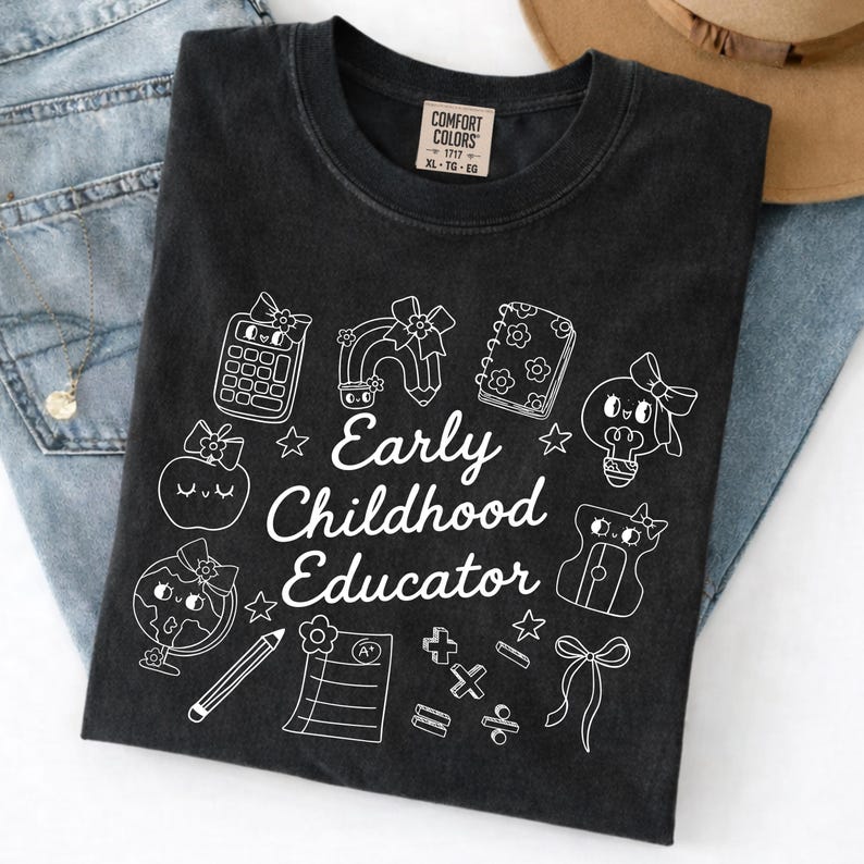 May include: Black t-shirt with white graphic illustrations and the text "Early Childhood Educator." The design includes a calculator, rainbow, notebook, lightbulb, apple, globe, pencil, and other school-themed elements. The shirt is a Comfort Colors brand.