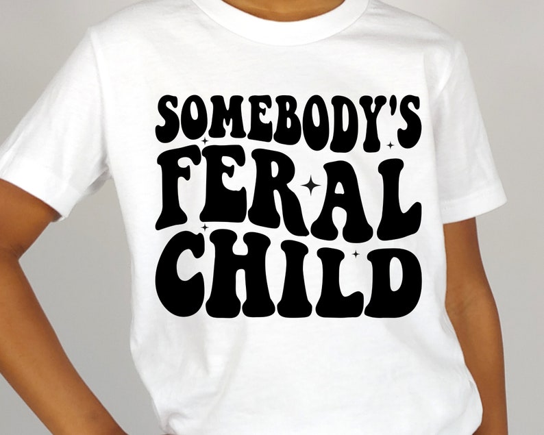 May include: White t-shirt with black text that reads "Somebody's Feral Child" in a retro font.