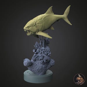 May include: A detailed sculpture of a prehistoric fish, the *Dunkleosteus*, with an open mouth, displayed above a coral reef base. The sculpture is a light olive green colour, mounted on a round, light blue base.