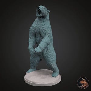 以下が含まれることがあります： 口を開けた立ち姿の、ティール色のクマの置物。クマは丸いライトグレーの台座に乗っています。この置物は、詳細で質感のある毛皮の外観をしています。