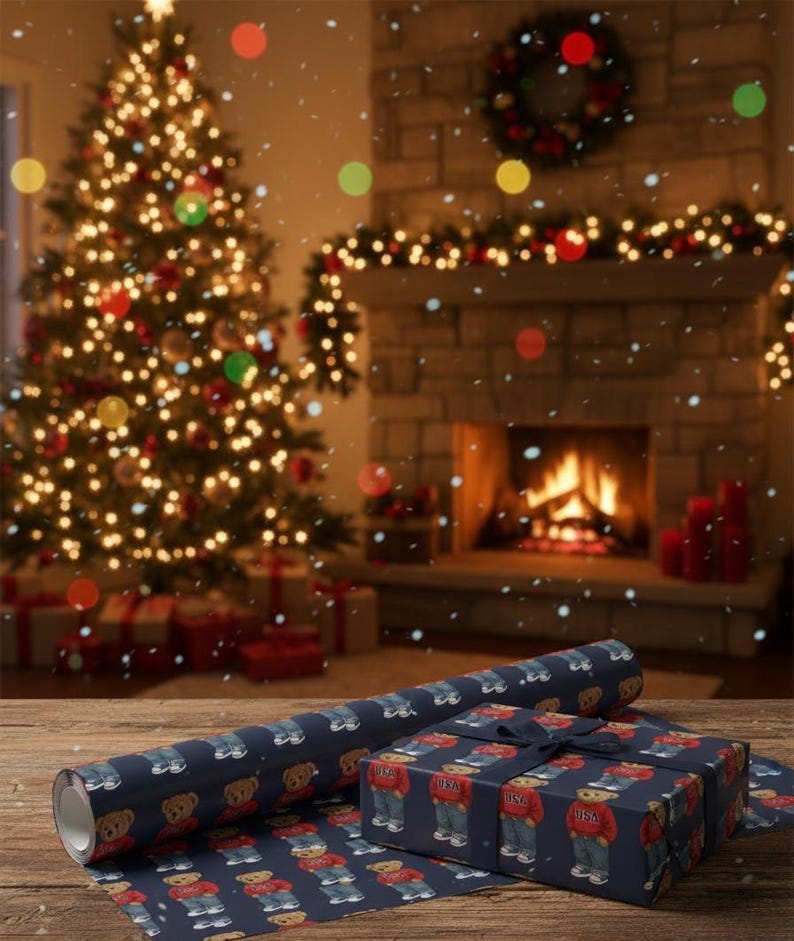 Op de afbeelding: Kerstsc&egrave;ne met een versierde boom, een open haard en ingepakte cadeaus. De cadeaus en het cadeaupapier hebben een marineblauwe achtergrond met een herhaald patroon van teddyberen met rode truien en jeans. Een rol bijpassend cadeaupapier is ook zichtbaar.