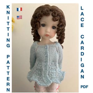 Puede incluir: Una muñeca con un cárdigan de encaje tejido de color azul claro con un dobladillo festoneado. El cárdigan tiene mangas largas y está abotonado por delante. La imagen también incluye el texto "KNITTING PATTERN" y "LACE CARDIGAN PDF".
