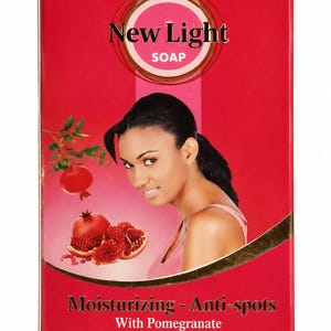 May include: A rectangular red box of New Light soap featuring a graphic of a person, pomegranate fruit, and text that reads Moisturizing - Anti-spots With Pomegranate extract and Collagen. The packaging design includes a circular logo at the top.