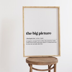 Op de afbeelding: Een ingelijst print met een witte achtergrond en zwarte tekst. De tekst definieert de zin "het grote plaatje" als een "majestueus concept dat vaak wordt besproken maar zelden wordt begrepen, waar iedereen beweert het te begrijpen, maar niemand het echt kan beschrijven."