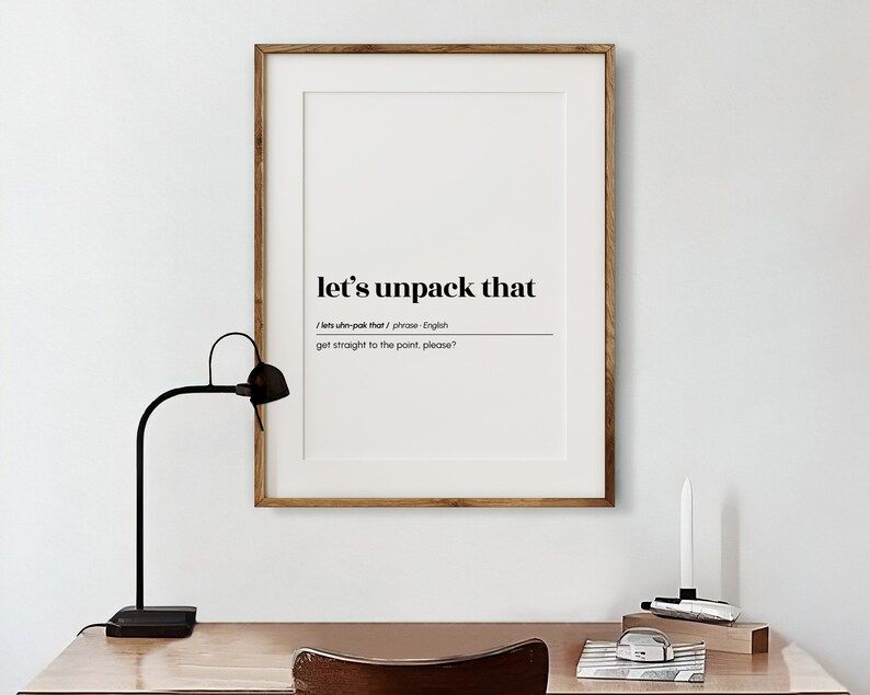 May include: A framed print with a black and white design. The text reads "let's unpack that /lets uhn-pak that/ phrase - English get straight to the point, please?"