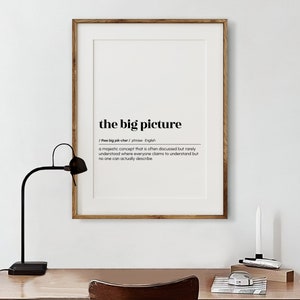 Op de afbeelding: Een ingelijst print met een zwart-witte definitie van de uitdrukking "het grote plaatje". De definitie luidt: "Een majestueus concept dat vaak wordt besproken, maar zelden wordt begrepen, waar iedereen beweert het te begrijpen, maar niemand het echt kan beschrijven."
