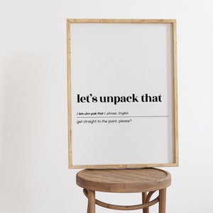 May include: A framed print with the text "let's unpack that" and the definition "get straight to the point, please?" in black text on a white background.