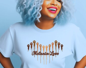 May include: A light blue t-shirt with a graphic of raised fists in different skin tones dripping with brown paint. The text "Melanin Love" is printed below the fists.