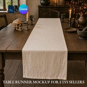 May include: A rectangular, light beige linen table runner laid flat across a dark brown wooden table. The runner features a simple hemmed edge and a textured fabric surface, centered on the table surface with visible stitching along the borders.