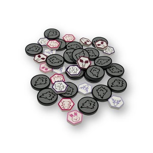 May include: A collection of round, white game tokens with various black and purple illustrations. The tokens are scattered on a white surface. Some of the tokens have pink accents.