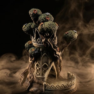 May include: A detailed incense burner in the form of a fantasy tree, featuring multiple rounded, leafy tops. The structure is a muted grey-green with small, colourful floral accents. The design includes arched doorways and a decorative railing, set against a dark background with smoky effects.