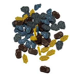 Könnte beinhalten: Eine Sammlung von hölzernen Spielsteinen in Blau, Braun und Gelb. Die Steine sind in Form von Fischen, Baumstämmen und Weizenähren.