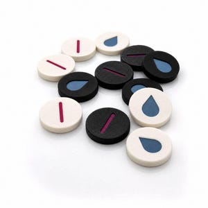 Puede incluir: Una colección de fichas circulares en blanco y negro. Algunas fichas presentan un icono de gota azul, mientras que otras muestran una única línea vertical magenta. Las fichas están dispuestas en un grupo disperso con colores contrastantes.
