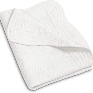 May include: White quilted throw blanket with a scalloped edge and a delicate floral pattern.