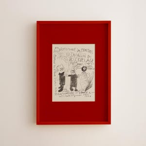 May include: A framed black and white artwork with a red frame. The artwork features three cartoon figures and French text, including "REPERTOIRE DES PANTINS" and "LA CHANSON DU DECERVELAGE". The artwork is signed and dated 1979.