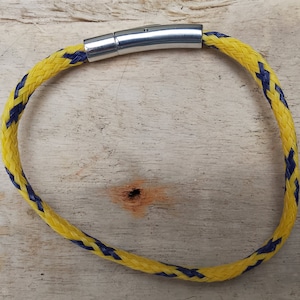 May include: A yellow and blue braided rope bracelet with a silver metal clasp.