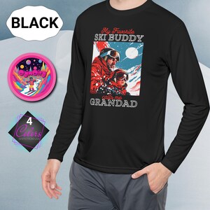 May include: Black long-sleeved shirt featuring a ski-themed graphic with the text "My Favorite Ski Buddy calls me GRANDAD". The graphic depicts a man and child in ski attire against a snowy mountain scene. The shirt has a crew neck.