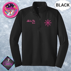 May include: Black long-sleeved pullover with a quarter-zip collar. The shirt features the text "Ski la Vie" and a pink burst design. A circular patch with a skier is visible. The word "BLACK" is in a white oval.