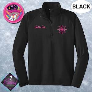 May include: Black long-sleeve pullover with a quarter-zip collar. The text "Ski la Vie" is embroidered in pink, along with a pink burst design. A circular sticker with a skier is in the upper left corner. The word "BLACK" is in a white bubble.